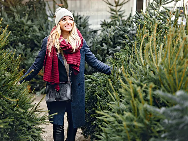Frau lächelnd beim Tannenbaumkauf