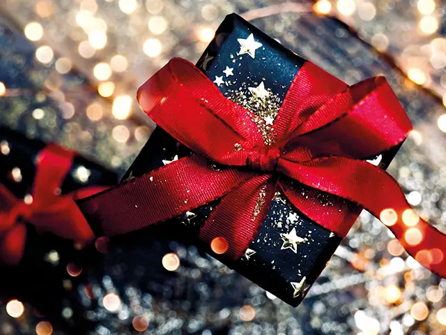 Draufsicht eines weihnachtlichen Geschenks auf einem Untergrund mit Glitter und Lichtdekoration